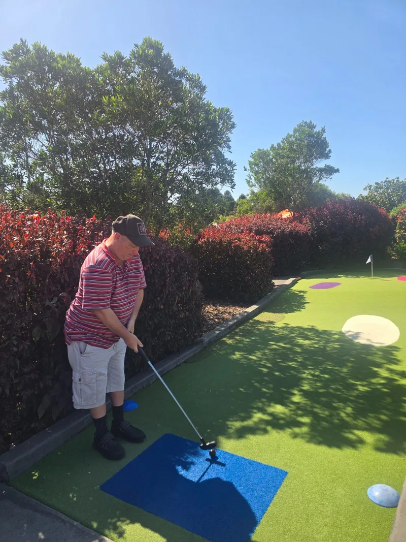 A participant playing mini golf in the sunshine