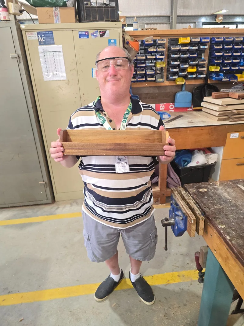 A participant proudly showing off a woodwork project